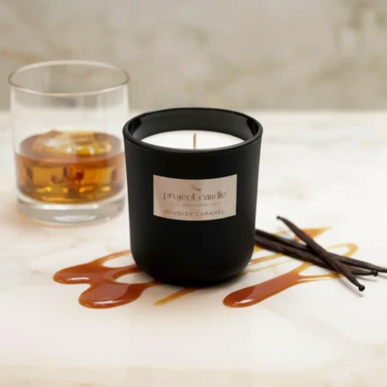 Χειροποίητο αρωματικό κερί Whiskey Caramel σε μαύρο γυάλινο δοχείο, με ζεστό άρωμα καραμέλας.