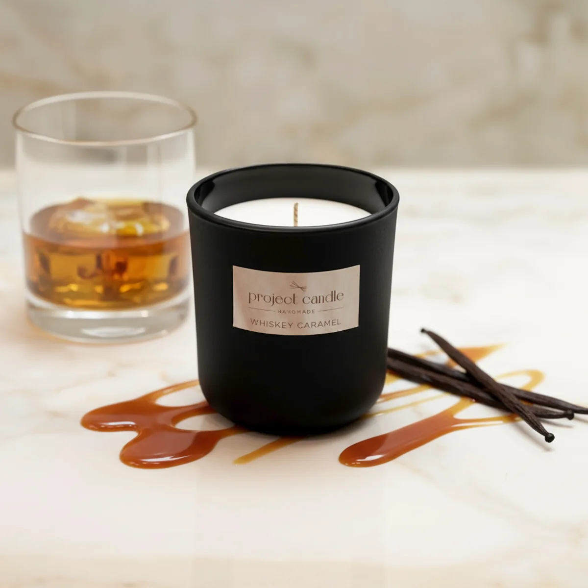 Χειροποίητο αρωματικό κερί Whiskey Caramel σε μαύρο γυάλινο δοχείο, με ζεστό άρωμα καραμέλας.